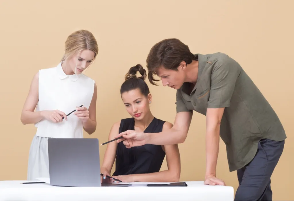 Photos of two young fashionable women and a men in front of a laptop in what seems to be a business meeting