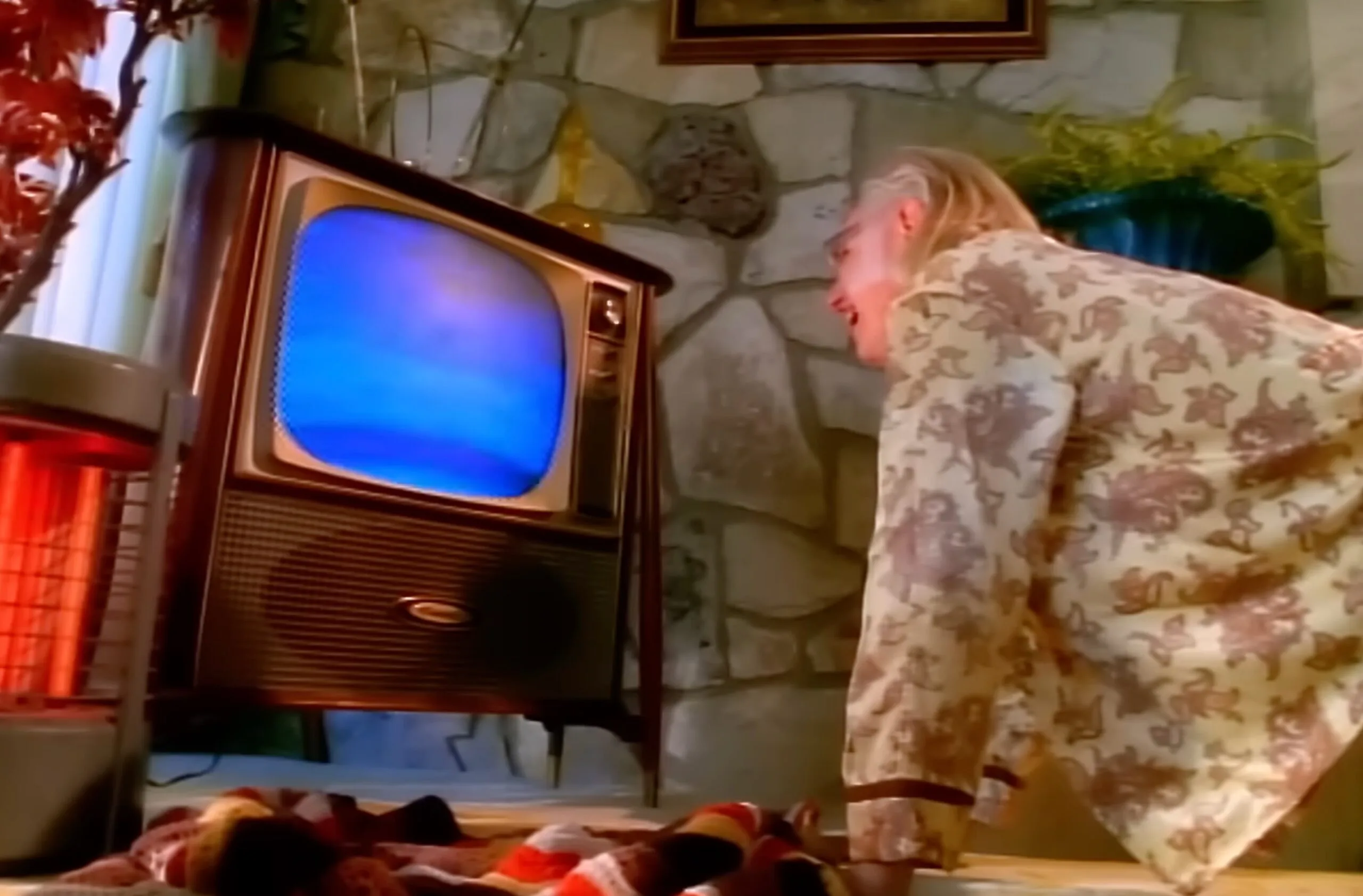 In a living room, a man sitting very close to a TV, starting at a blank screen